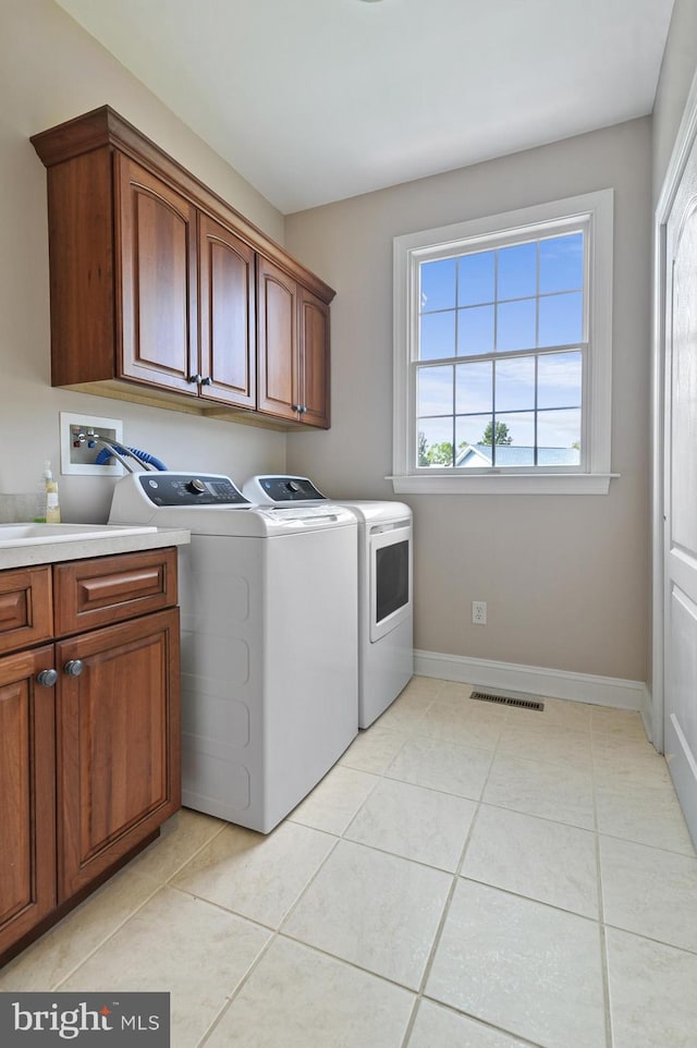 laundry area with washer and clothes dryer, light tile patterned floors, and cabinets