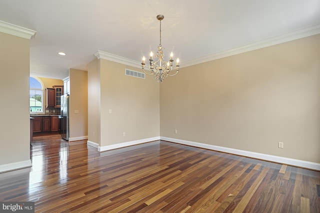 empty room featuring a notable chandelier, crown molding, and dark wood-type flooring