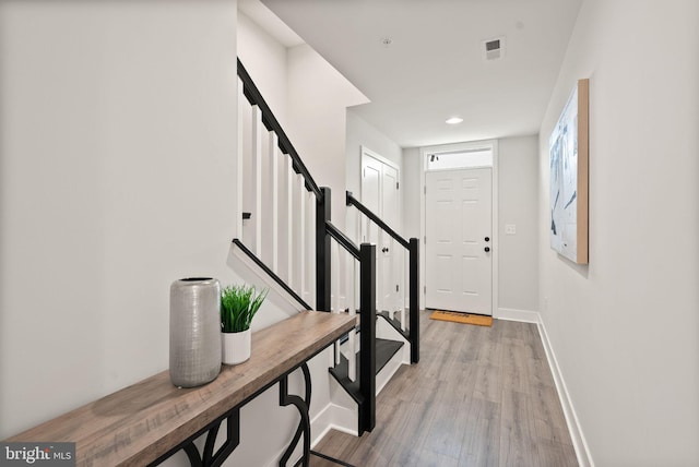 entryway with visible vents, baseboards, light wood-style flooring, and stairs