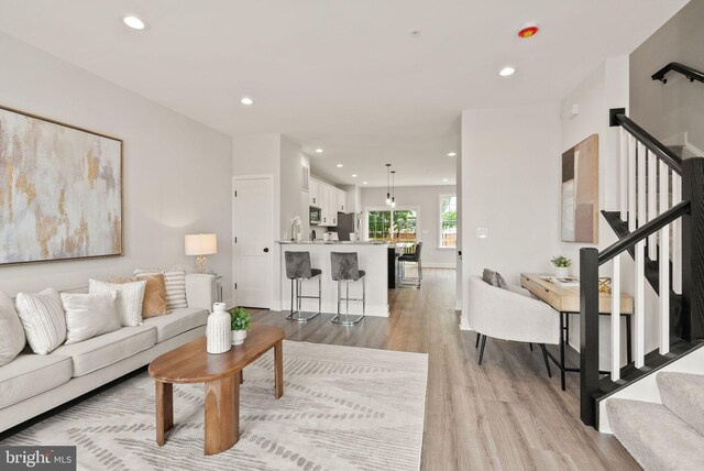 living room with light wood finished floors, stairway, and recessed lighting