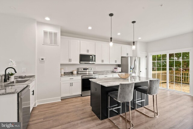 kitchen with white cabinets, light stone counters, appliances with stainless steel finishes, and sink