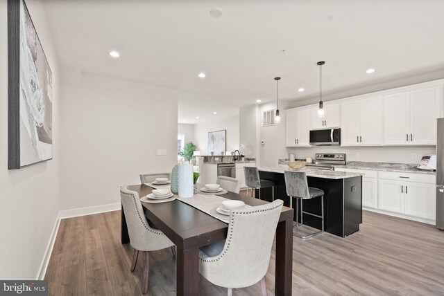 dining room with recessed lighting, light wood-type flooring, and baseboards