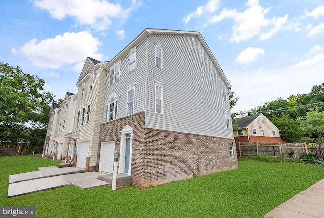 view of side of home with an attached garage, fence, brick siding, and a yard