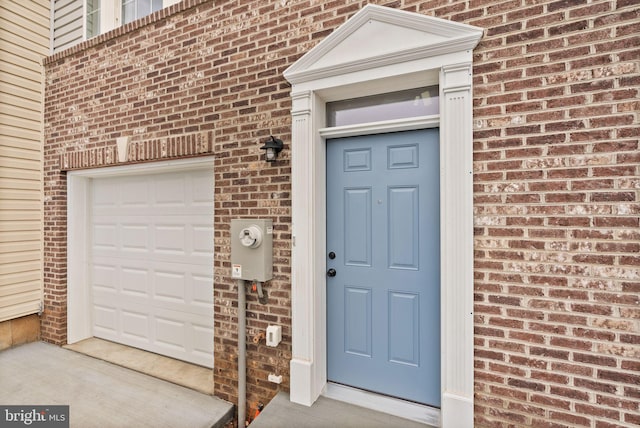 doorway to property with brick siding and an attached garage