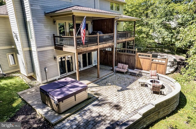 rear view of house featuring a fire pit, a wooden deck, and a patio