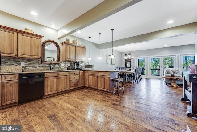 kitchen featuring dishwasher, decorative light fixtures, a chandelier, kitchen peninsula, and dark wood-type flooring