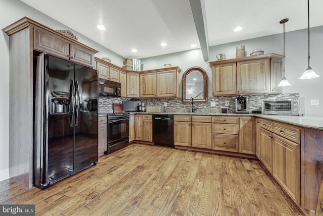 kitchen featuring black appliances, light hardwood / wood-style flooring, hanging light fixtures, decorative backsplash, and light stone counters