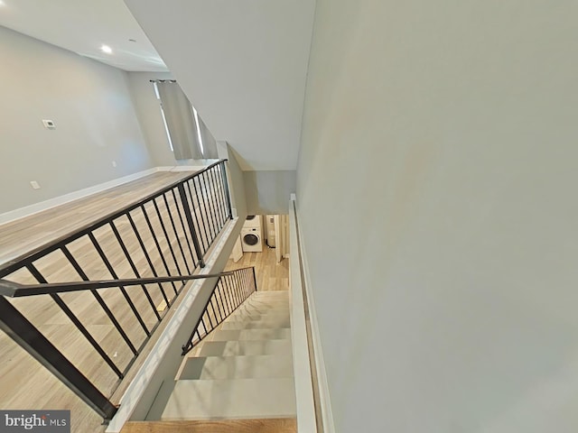 staircase with hardwood / wood-style floors and washer / clothes dryer