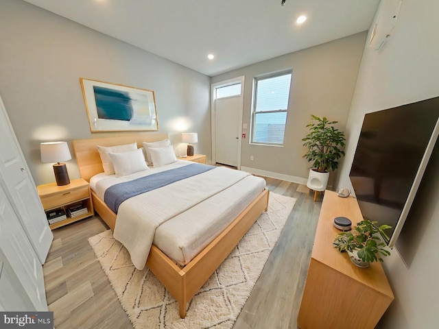 bedroom featuring a wall mounted AC and light hardwood / wood-style flooring