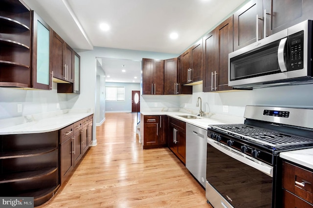 kitchen with appliances with stainless steel finishes, sink, dark brown cabinetry, and light hardwood / wood-style floors