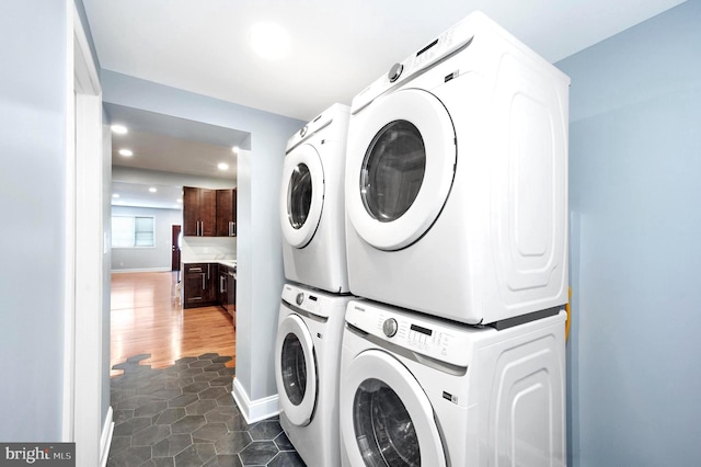 laundry room featuring dark wood-type flooring and stacked washer / dryer