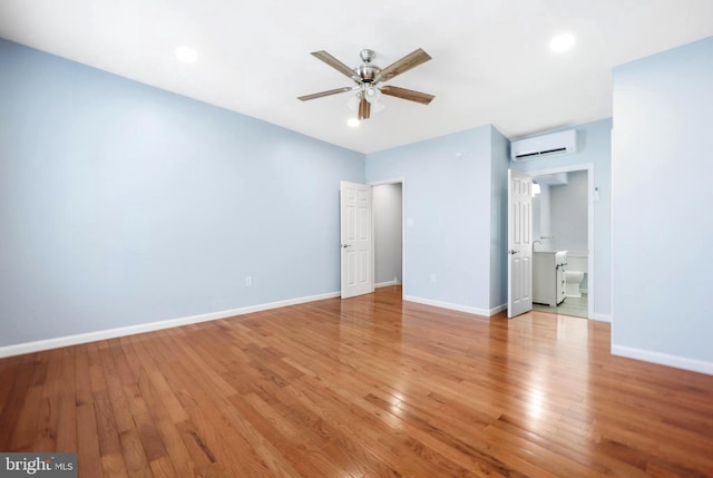 interior space featuring a wall mounted air conditioner, light hardwood / wood-style flooring, and ceiling fan