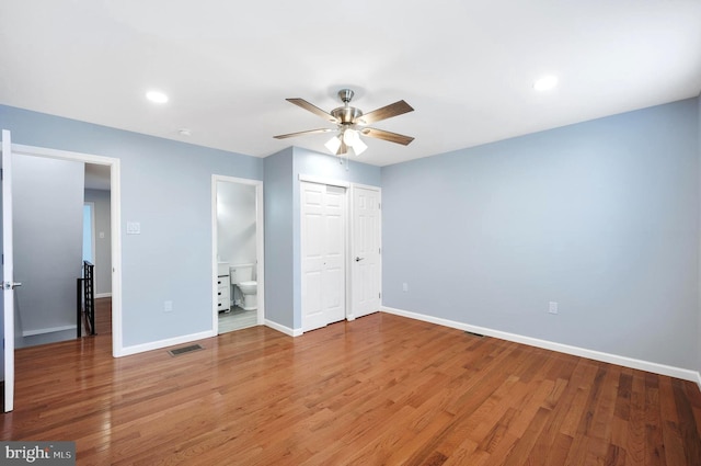 unfurnished bedroom with wood-type flooring, ensuite bathroom, ceiling fan, and a closet