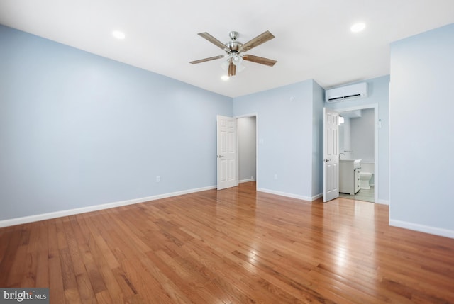 empty room with light wood-type flooring, a wall mounted AC, and ceiling fan