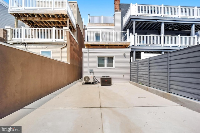 rear view of house with ac unit, a patio, and a balcony