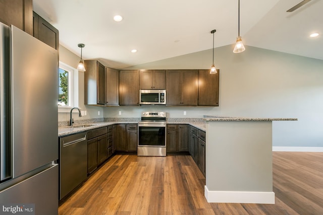 kitchen featuring stainless steel appliances, hanging light fixtures, lofted ceiling, and sink