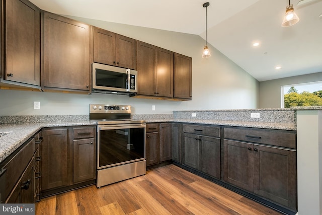 kitchen featuring hanging light fixtures, vaulted ceiling, light stone countertops, wood-type flooring, and stainless steel appliances