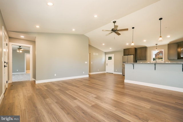 unfurnished living room featuring ceiling fan, vaulted ceiling, and light wood-type flooring