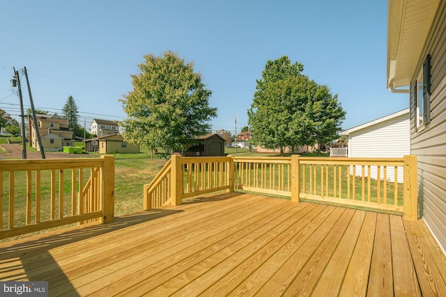 wooden terrace featuring a storage unit and a lawn