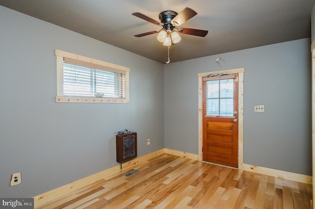 spare room with heating unit, ceiling fan, and light hardwood / wood-style flooring