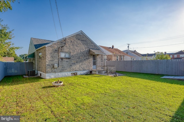 rear view of property featuring a yard and central air condition unit