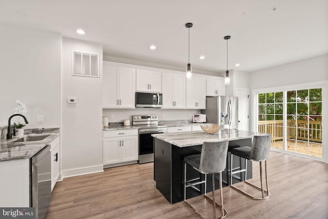 kitchen featuring light stone countertops, stainless steel appliances, white cabinetry, and sink