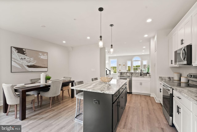 kitchen featuring hanging light fixtures, light hardwood / wood-style floors, white cabinets, stainless steel appliances, and a center island