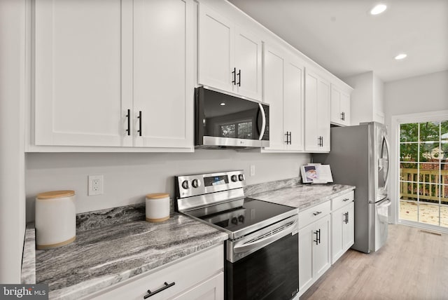 kitchen with light stone countertops, stainless steel appliances, white cabinets, and light hardwood / wood-style floors