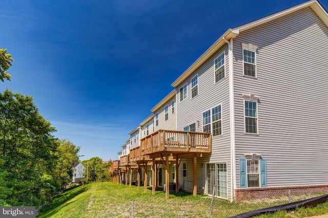 rear view of house with central AC unit, a deck, and a yard