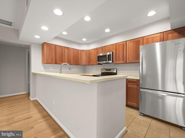 kitchen featuring kitchen peninsula, light hardwood / wood-style flooring, stainless steel appliances, and sink