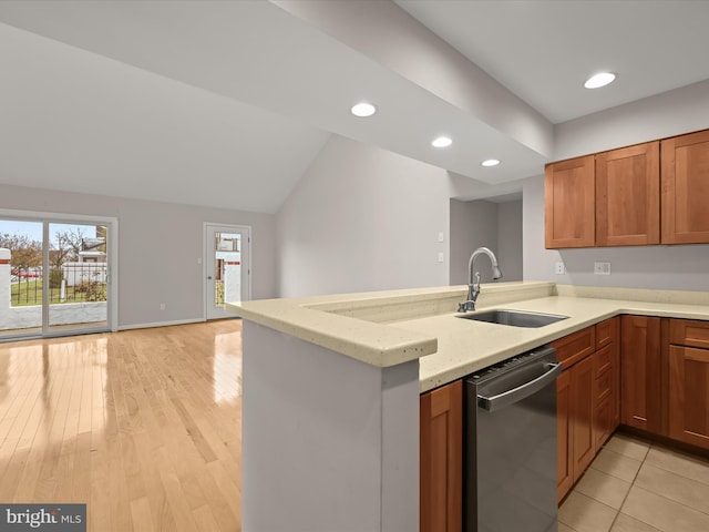 kitchen featuring sink, stainless steel dishwasher, kitchen peninsula, light hardwood / wood-style floors, and lofted ceiling