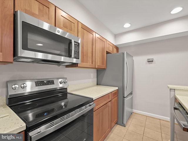 kitchen with light stone counters, light tile patterned flooring, and appliances with stainless steel finishes