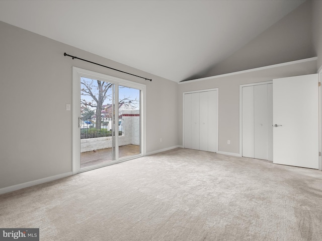 unfurnished bedroom featuring access to exterior, carpet, high vaulted ceiling, and multiple closets