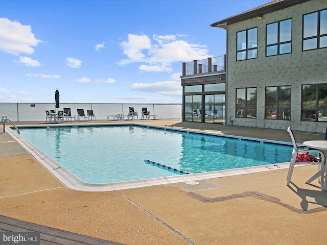 view of swimming pool featuring a patio area and a water view