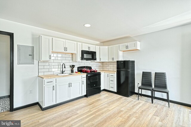 kitchen with sink, wooden counters, white cabinetry, black appliances, and light hardwood / wood-style floors