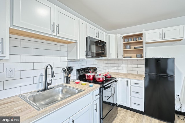 kitchen with decorative backsplash, white cabinets, black appliances, and sink