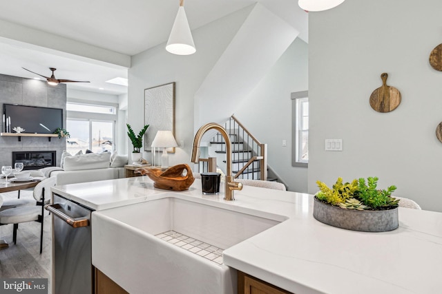 kitchen featuring light wood-type flooring, a fireplace, a sink, dishwasher, and open floor plan