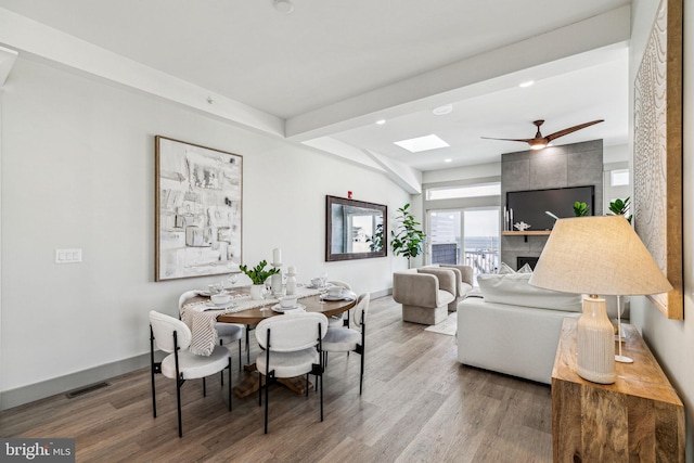 dining space featuring visible vents, beam ceiling, a skylight, wood finished floors, and a ceiling fan