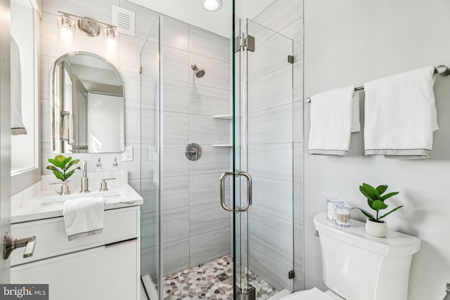 full bathroom featuring visible vents, a shower stall, toilet, and vanity