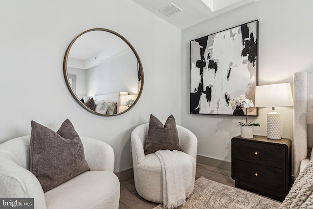 living area with visible vents, baseboards, and wood finished floors