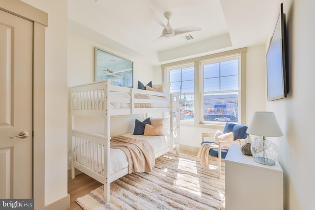 bedroom with ceiling fan, visible vents, and wood finished floors