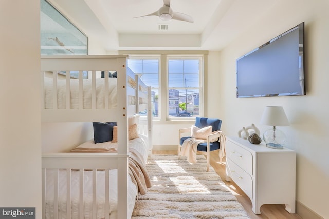 bedroom featuring baseboards, wood finished floors, visible vents, and ceiling fan