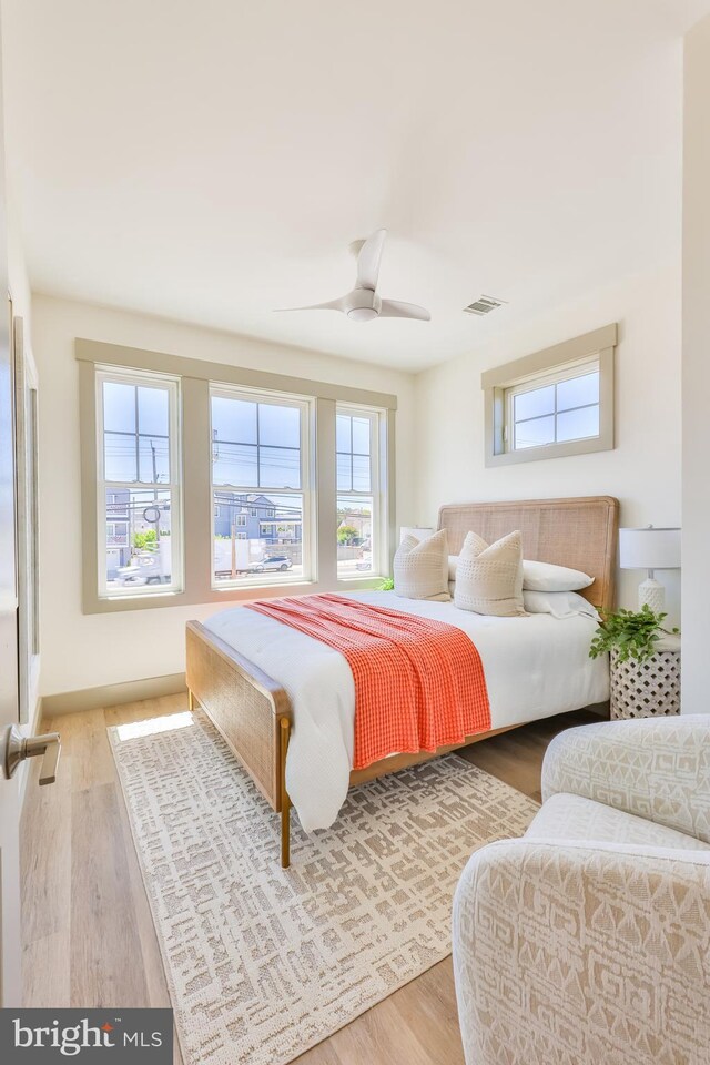 bedroom with ceiling fan, visible vents, and wood finished floors