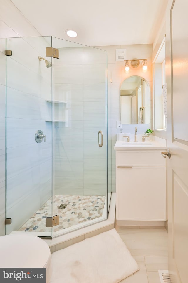 bathroom featuring visible vents, toilet, a stall shower, and vanity