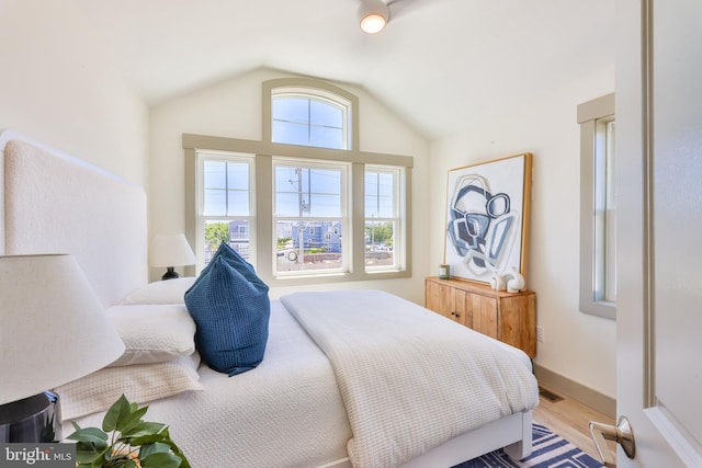 bedroom with baseboards, lofted ceiling, visible vents, and wood finished floors