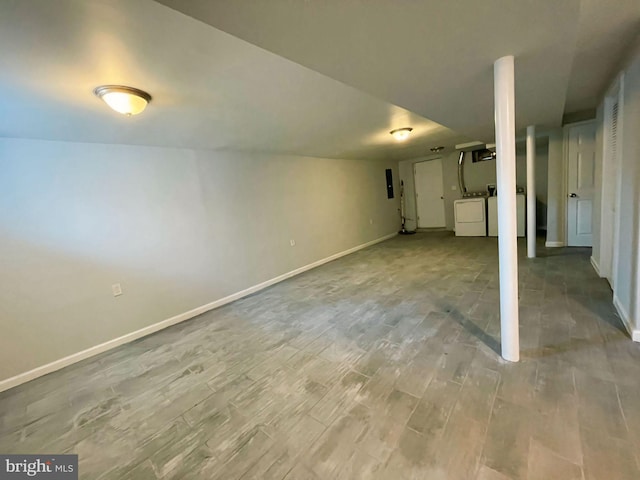 basement with light hardwood / wood-style floors, electric panel, and washing machine and clothes dryer