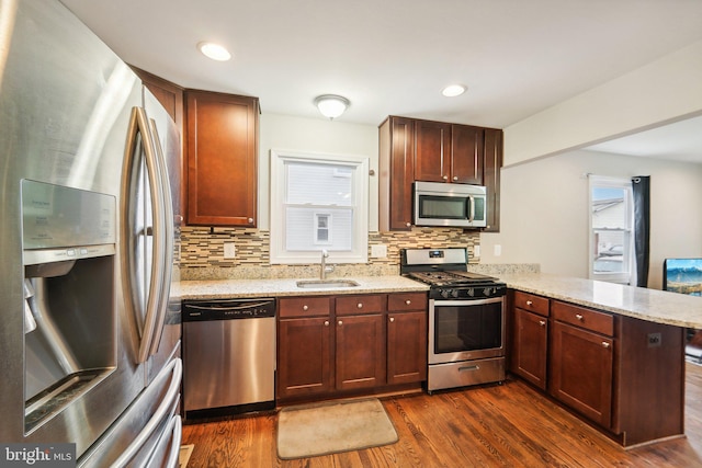 kitchen featuring appliances with stainless steel finishes, kitchen peninsula, sink, and dark wood-type flooring