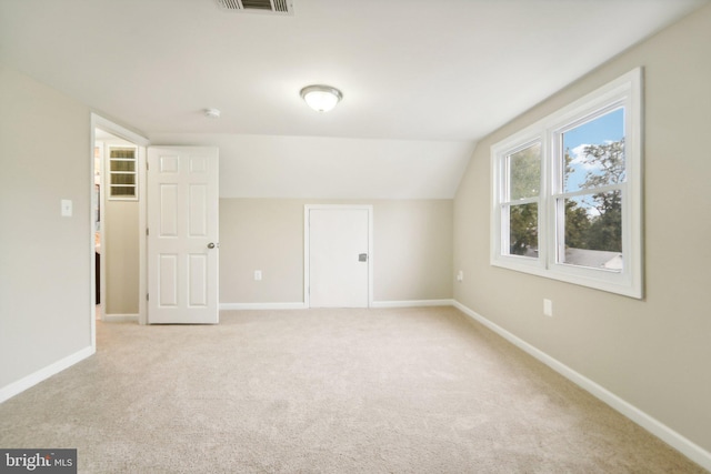 additional living space with light colored carpet and vaulted ceiling