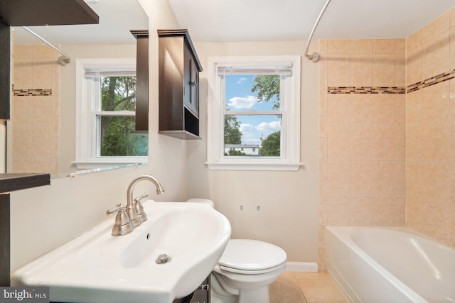 full bathroom with toilet, a healthy amount of sunlight, and tiled shower / bath