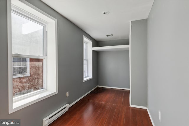 unfurnished room featuring a baseboard heating unit and dark hardwood / wood-style floors